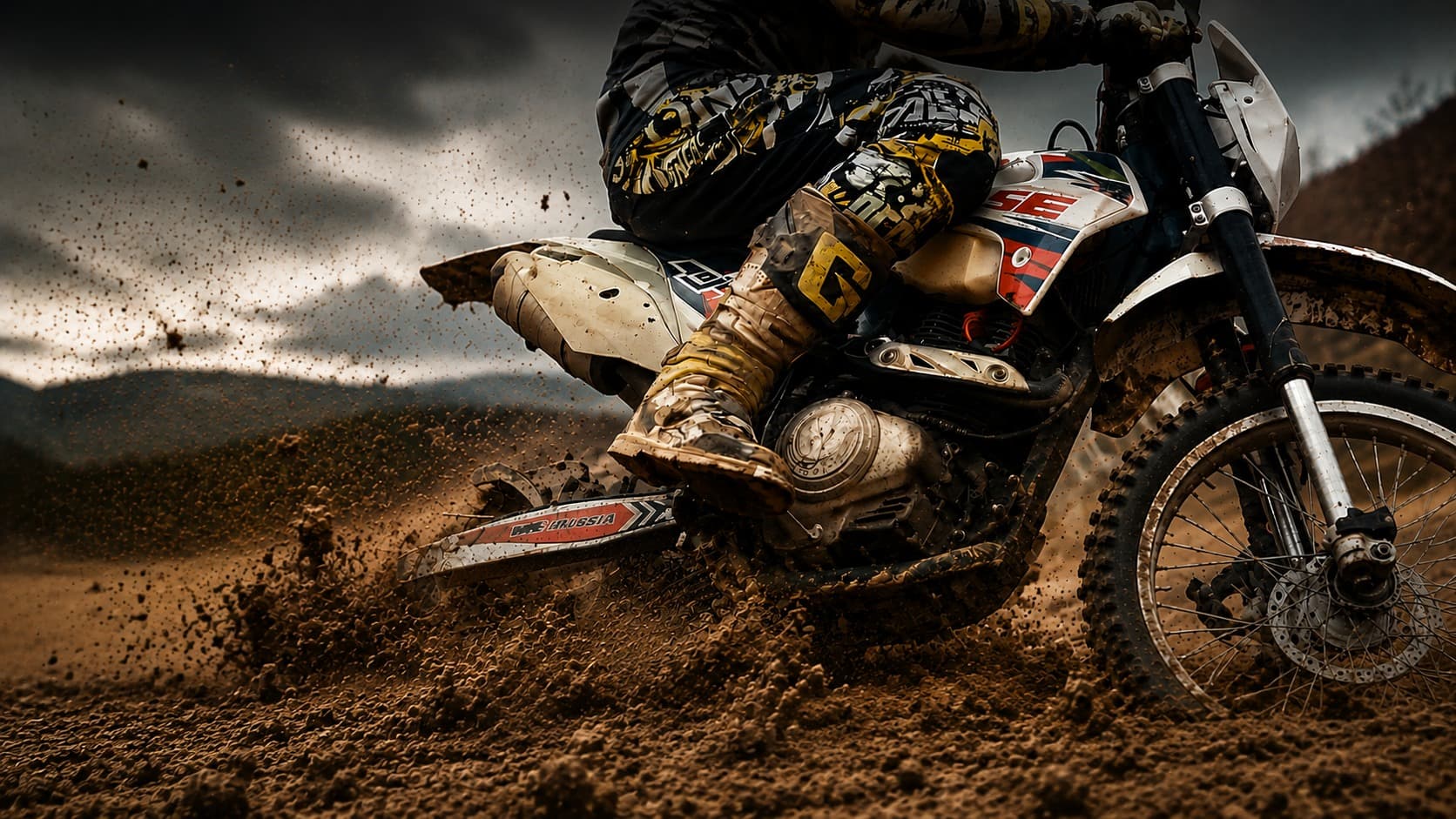 Dirt bike kicking up mud on a rugged trail under a stormy sky